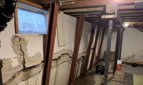 photo of a severely bowed basement wall in the process of being straightened with Gorilla Wall Braces
