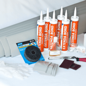 contents of the DIY basement waterproofing kit - DRY-UP vinyl baseboard to fix wet basements, corner pieces, tubes of adhesive, spray bottle, and install kit.